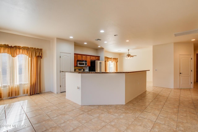 kitchen featuring stone counters, appliances with stainless steel finishes, light tile patterned floors, and ceiling fan