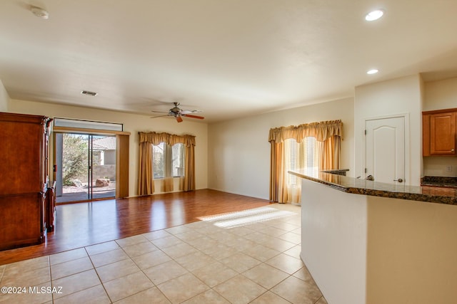 kitchen featuring ceiling fan, light hardwood / wood-style flooring, and dark stone counters