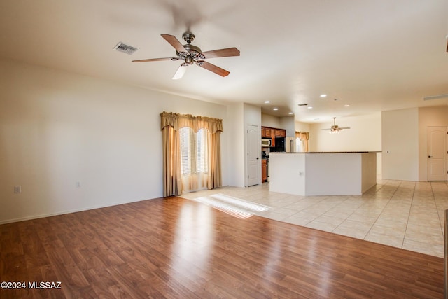 unfurnished living room with ceiling fan and light wood-type flooring