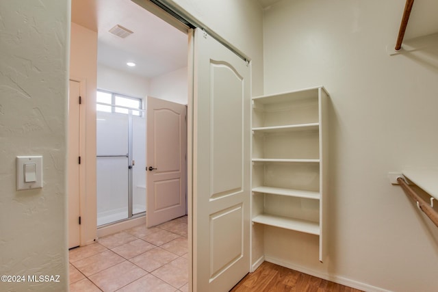 walk in closet featuring a barn door and light hardwood / wood-style flooring