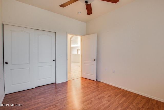 unfurnished bedroom featuring ceiling fan, light hardwood / wood-style floors, and a closet