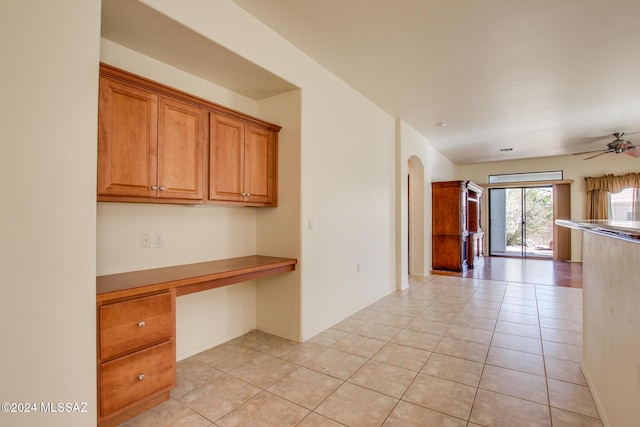 kitchen featuring ceiling fan, light tile patterned flooring, and built in desk