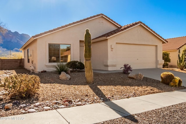 view of front of house with fence, driveway, stucco siding, a garage, and a mountain view