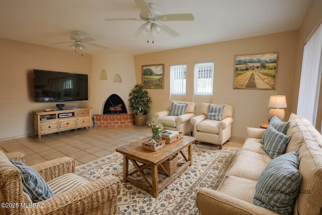 unfurnished living room with ceiling fan, a healthy amount of sunlight, light tile patterned floors, and a fireplace