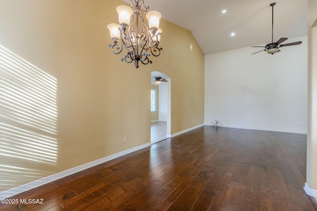 empty room with high vaulted ceiling, dark wood-type flooring, and ceiling fan with notable chandelier