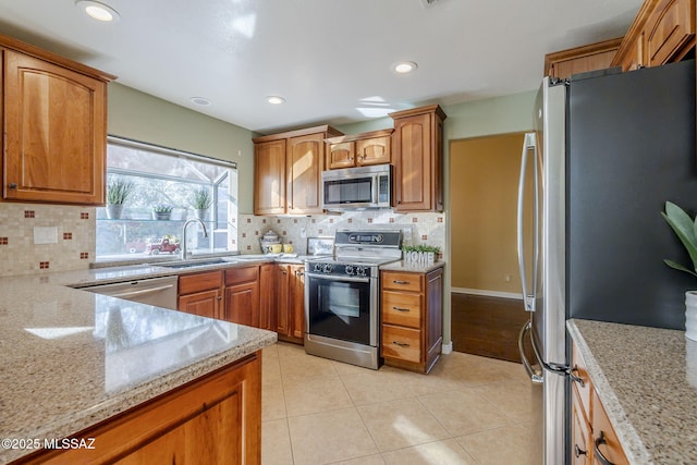 kitchen with sink, appliances with stainless steel finishes, tasteful backsplash, light tile patterned flooring, and light stone counters