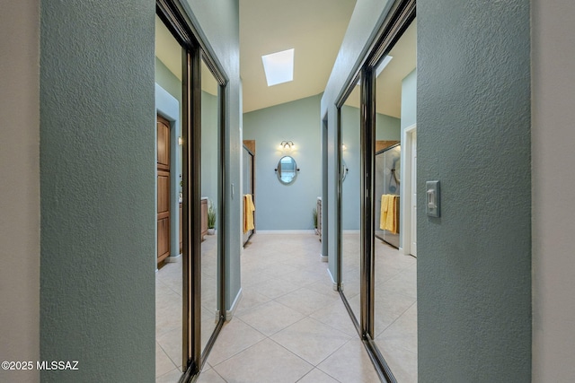 hallway with light tile patterned floors and vaulted ceiling with skylight