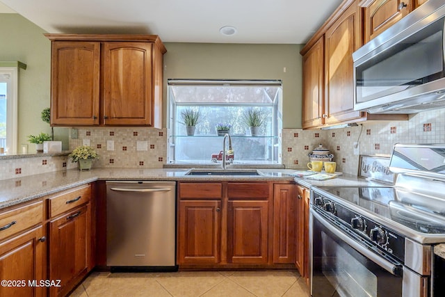 kitchen featuring decorative backsplash, sink, light stone counters, and stainless steel appliances