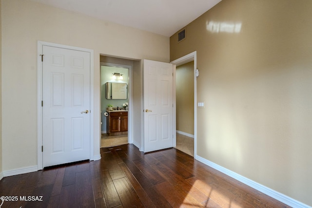 unfurnished bedroom with ensuite bathroom, sink, and dark wood-type flooring