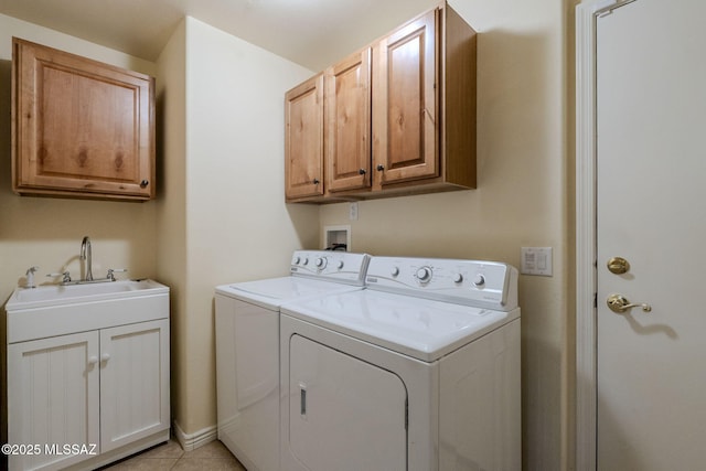 clothes washing area featuring cabinets, light tile patterned floors, sink, and washing machine and clothes dryer