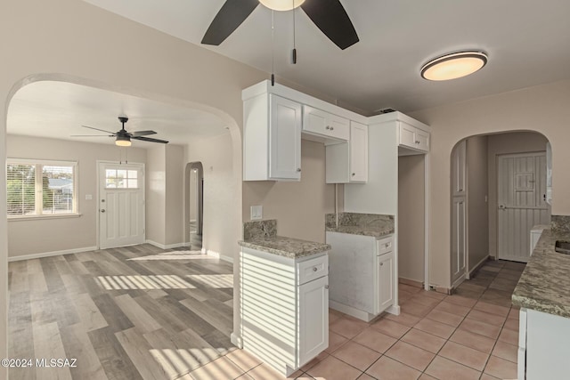 kitchen featuring white cabinets, ceiling fan, light hardwood / wood-style floors, and light stone countertops