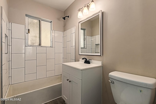 full bathroom with hardwood / wood-style flooring, vanity, tiled shower / bath combo, and toilet