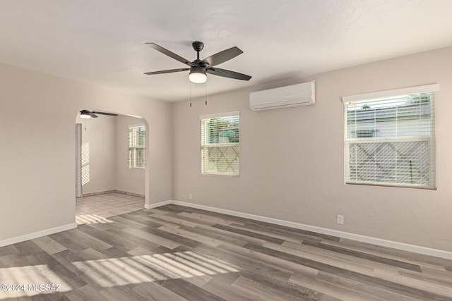 spare room featuring ceiling fan, wood-type flooring, and an AC wall unit