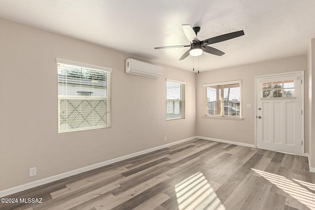 entrance foyer with hardwood / wood-style flooring, ceiling fan, and a wall unit AC