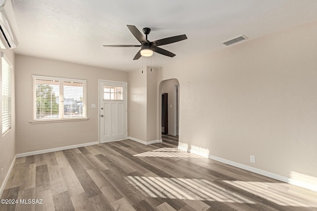 interior space with an AC wall unit, ceiling fan, and hardwood / wood-style floors