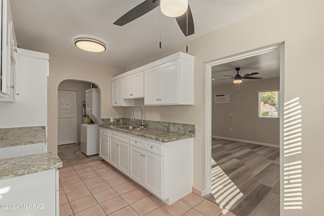 kitchen with light stone counters, light wood-type flooring, white cabinetry, and sink