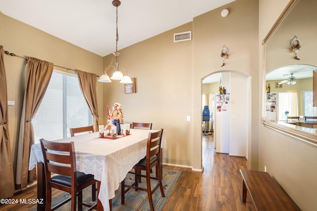 dining space with lofted ceiling, dark hardwood / wood-style flooring, and ceiling fan with notable chandelier