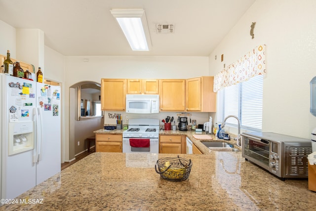 kitchen with light brown cabinets, light stone counters, white appliances, and sink