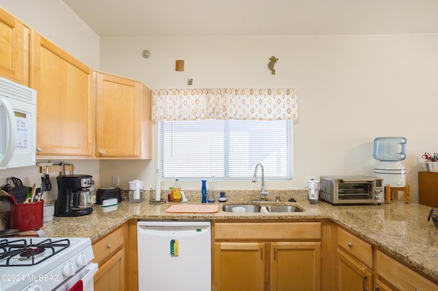 kitchen featuring light stone countertops, white appliances, sink, and light brown cabinetry