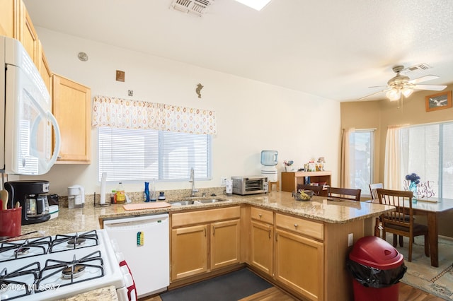 kitchen with kitchen peninsula, sink, a healthy amount of sunlight, and white appliances