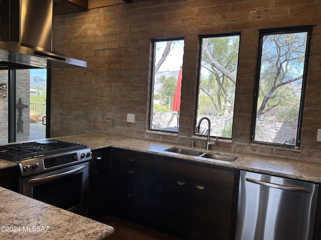 kitchen featuring appliances with stainless steel finishes, sink, a healthy amount of sunlight, and wall chimney range hood