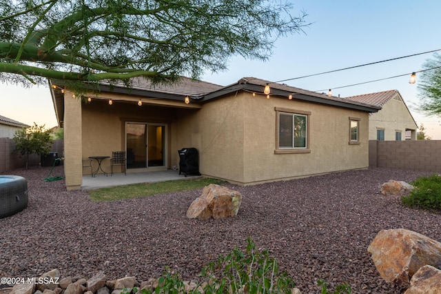 back house at dusk featuring a patio