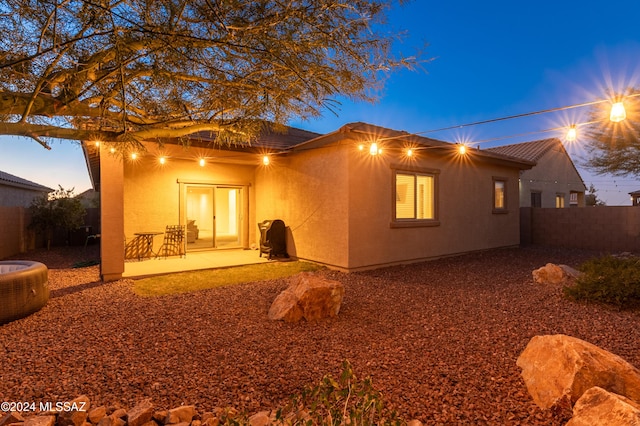 back house at dusk with a patio area