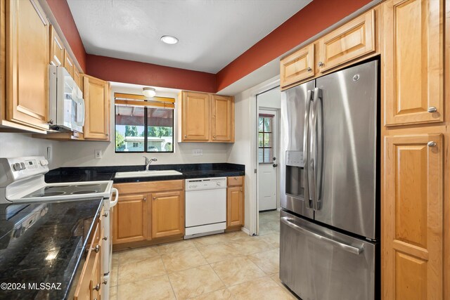 kitchen with a healthy amount of sunlight, white appliances, sink, and light tile patterned floors