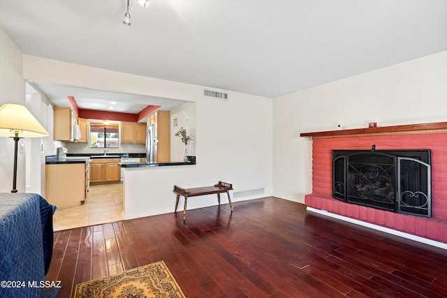 living room with a fireplace, light hardwood / wood-style floors, and sink