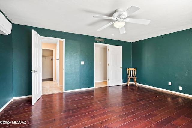 unfurnished bedroom featuring a closet, dark hardwood / wood-style floors, a spacious closet, and ceiling fan