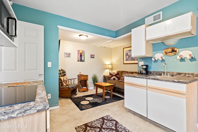 kitchen with white cabinets, light tile patterned floors, black electric cooktop, and sink