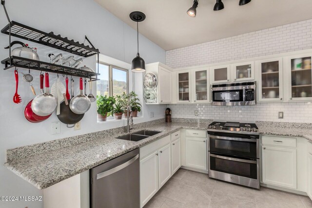 kitchen featuring sink, white cabinetry, hanging light fixtures, light stone countertops, and stainless steel dishwasher