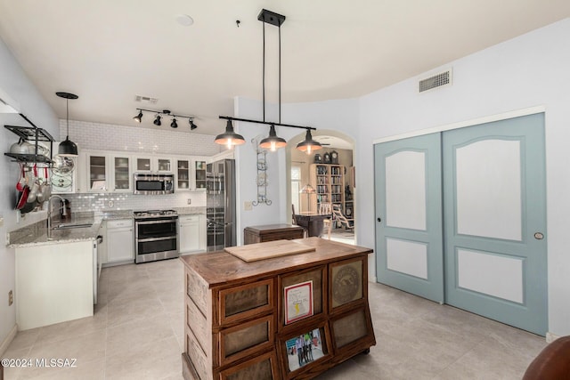 kitchen with sink, white cabinetry, light stone counters, decorative light fixtures, and stainless steel appliances