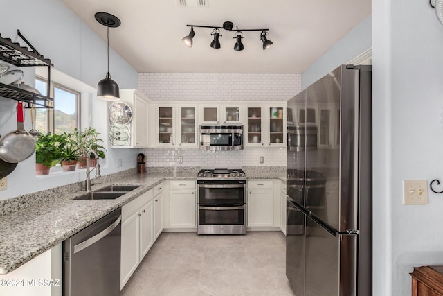 kitchen featuring sink, appliances with stainless steel finishes, white cabinetry, light stone counters, and decorative light fixtures