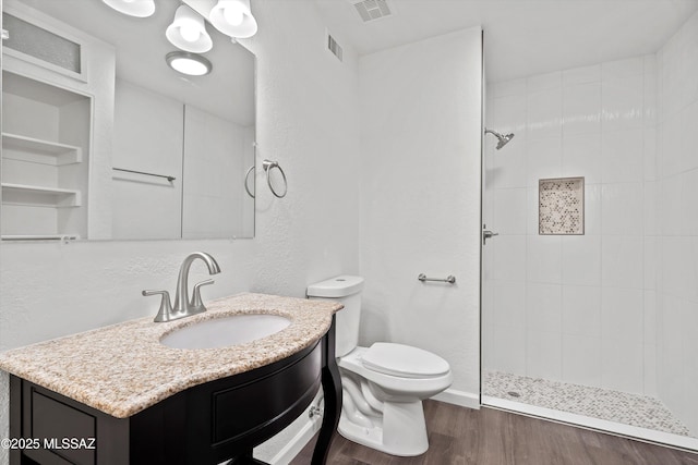 bathroom featuring toilet, vanity, tiled shower, and hardwood / wood-style flooring