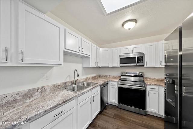 kitchen with stainless steel appliances, dark hardwood / wood-style floors, white cabinets, light stone counters, and sink