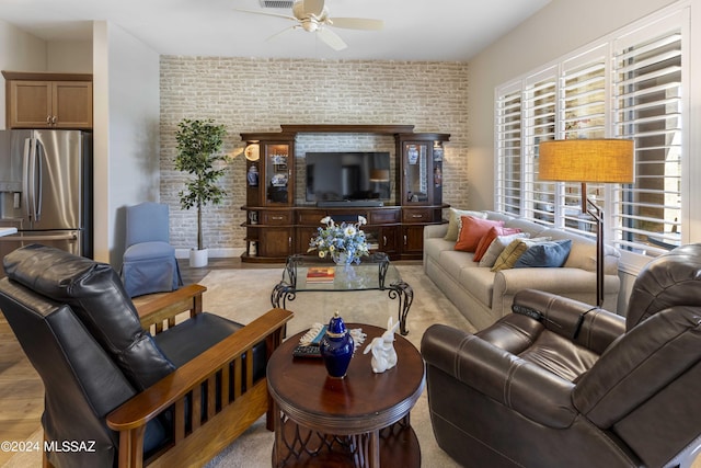 living room featuring brick wall, light wood-type flooring, and ceiling fan