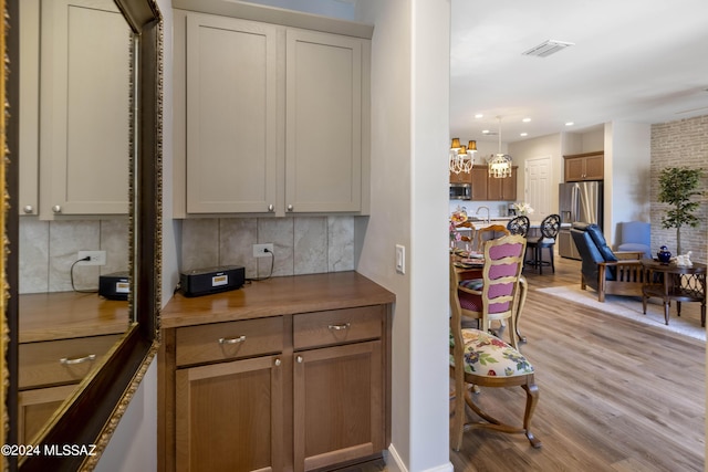 bar with decorative light fixtures, light hardwood / wood-style floors, tasteful backsplash, wood counters, and appliances with stainless steel finishes