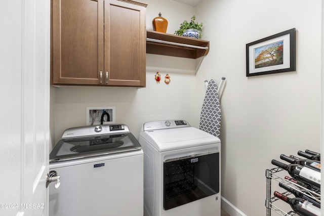 clothes washing area featuring cabinets and separate washer and dryer