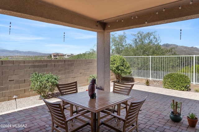 view of patio with a fenced backyard, a mountain view, and outdoor dining area