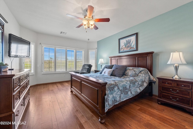 bedroom with ceiling fan, dark wood finished floors, visible vents, and baseboards