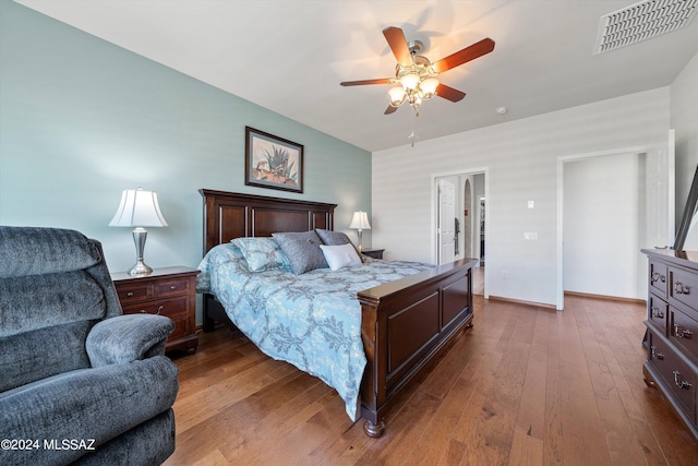 bedroom with a ceiling fan, wood finished floors, visible vents, and baseboards