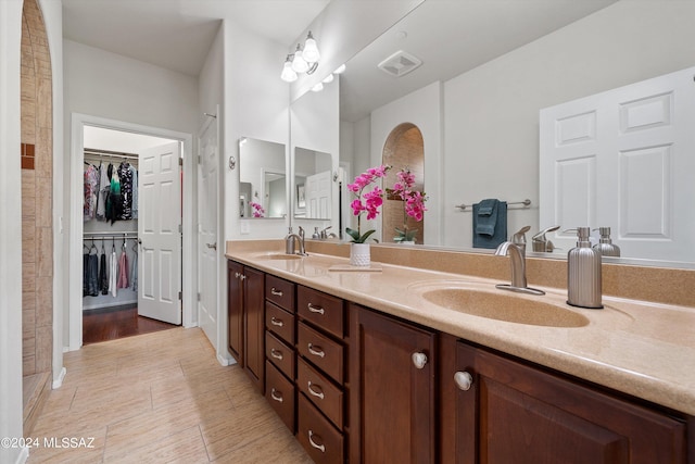 full bath with visible vents, a sink, a spacious closet, and double vanity