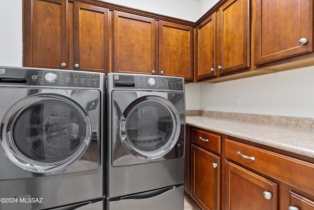 washroom featuring cabinet space and washer and clothes dryer