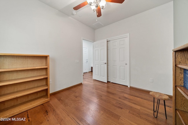 unfurnished bedroom with a ceiling fan, visible vents, baseboards, and wood finished floors