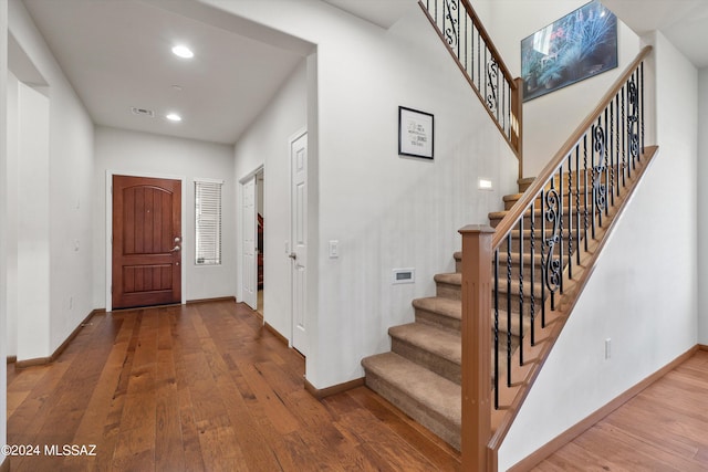 foyer featuring stairs, recessed lighting, wood finished floors, and baseboards