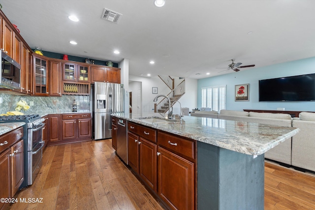 kitchen with a kitchen island with sink, a sink, visible vents, open floor plan, and appliances with stainless steel finishes