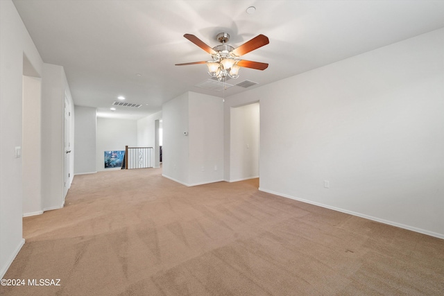 spare room featuring light colored carpet, visible vents, ceiling fan, and baseboards