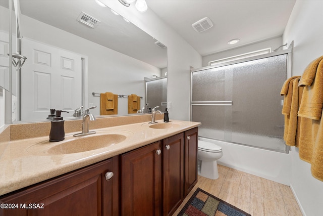 full bath featuring bath / shower combo with glass door, a sink, and visible vents