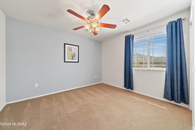 spare room with light carpet, baseboards, visible vents, and a ceiling fan